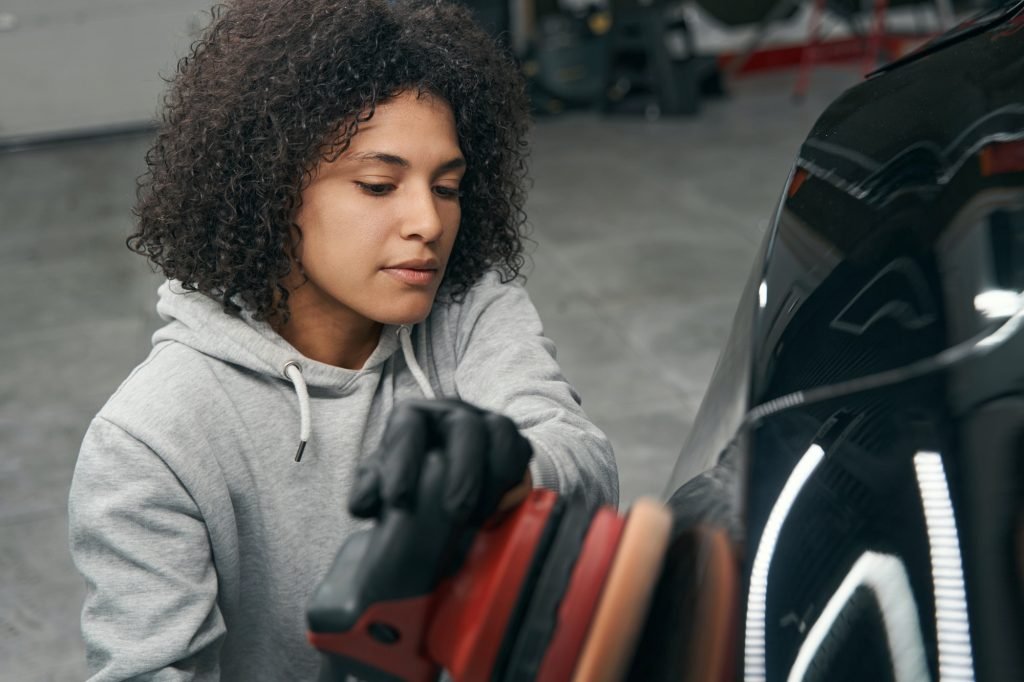Tranquil concentrated female worker buffing motor vehicle